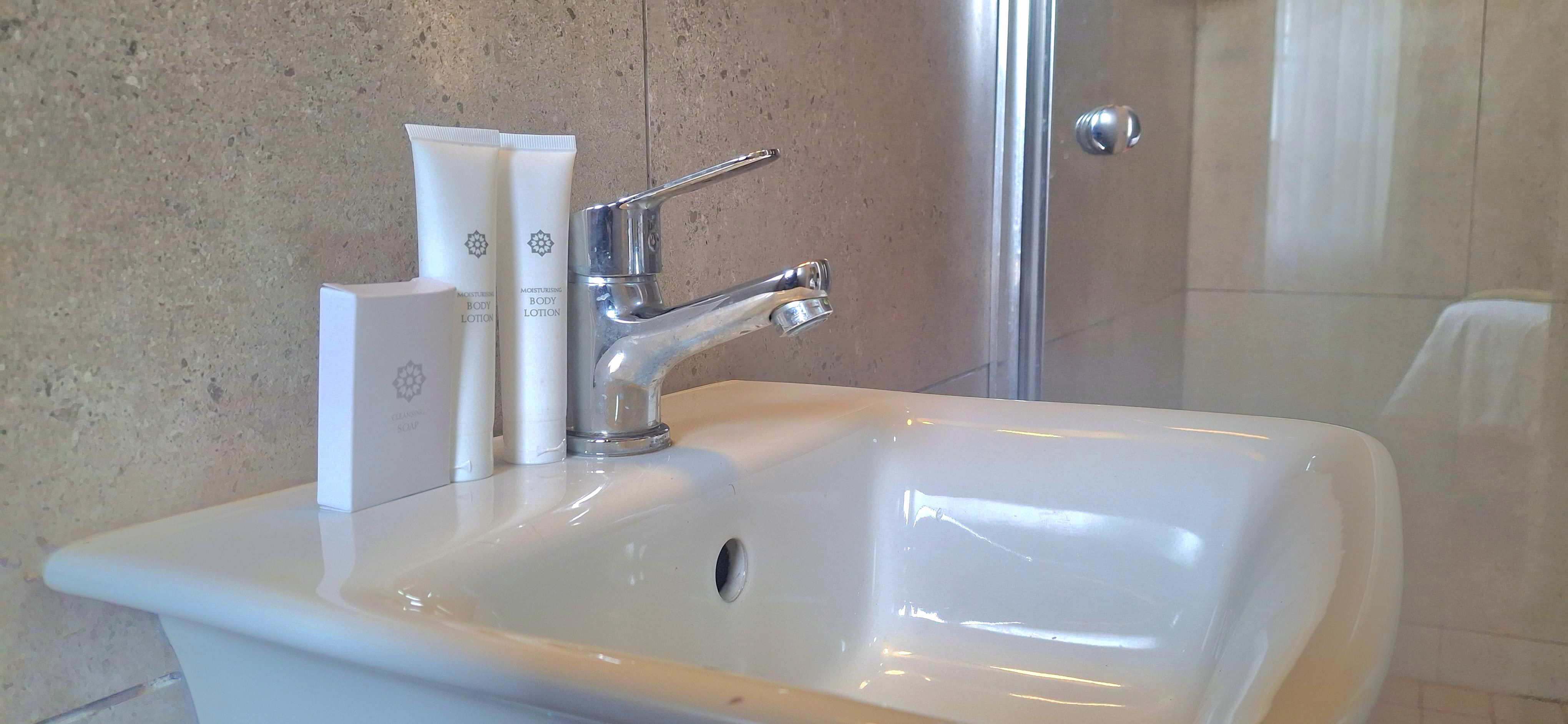 Bathroom sink with guest toiletries and shower