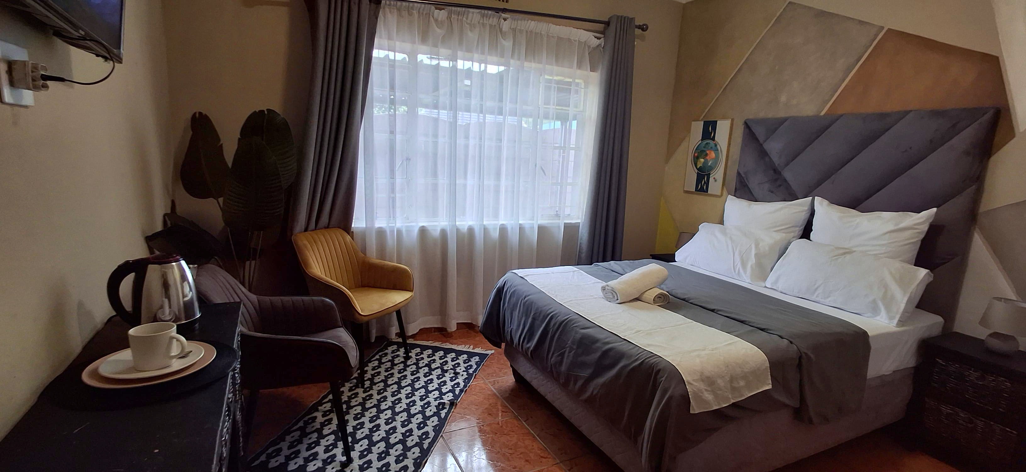 Spacious double room with tufted headboard and yellow armchair